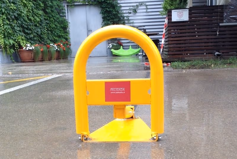 Žuta automatska parking barijera sa podignutim lukom na asfaltu.