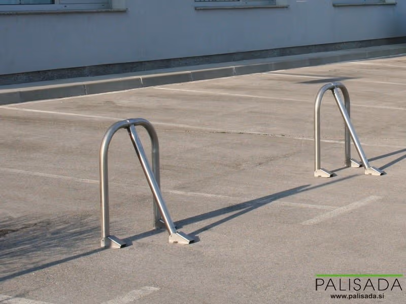 Dve podignute metalne ručne parking barijere na obeleženim parking mestima.