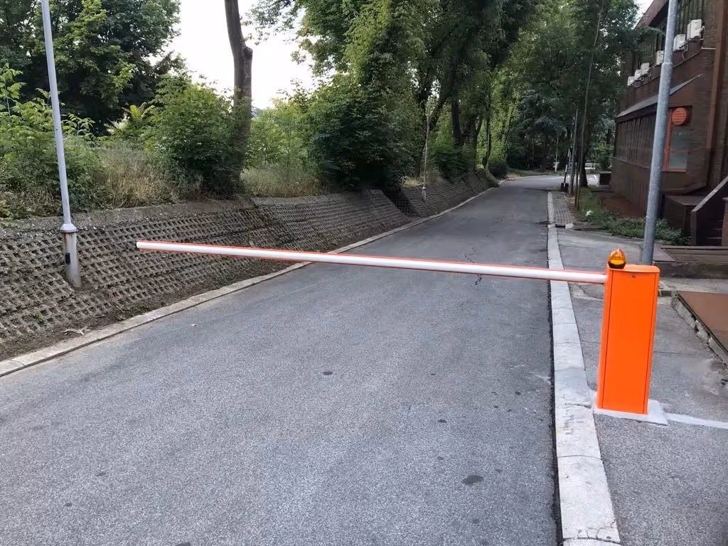 Narandžasta parking rampa sa spuštenom belom rukom preko asfaltiranog prilaza.